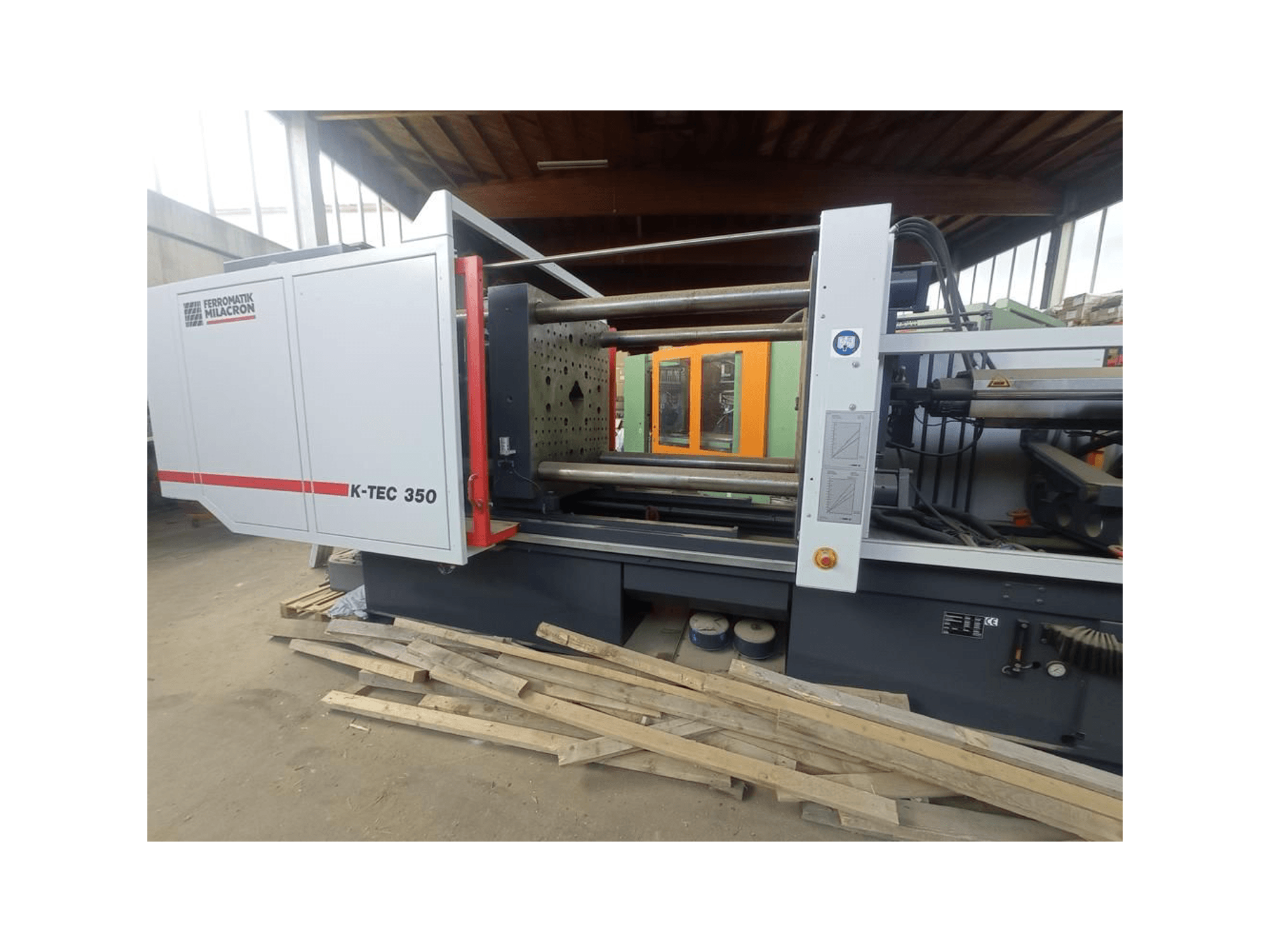 K-TEC 350 tvrtke Ferromatik Milacron, gledan sa strane, prikazuje svoje složene strojeve i operativne kontrole.